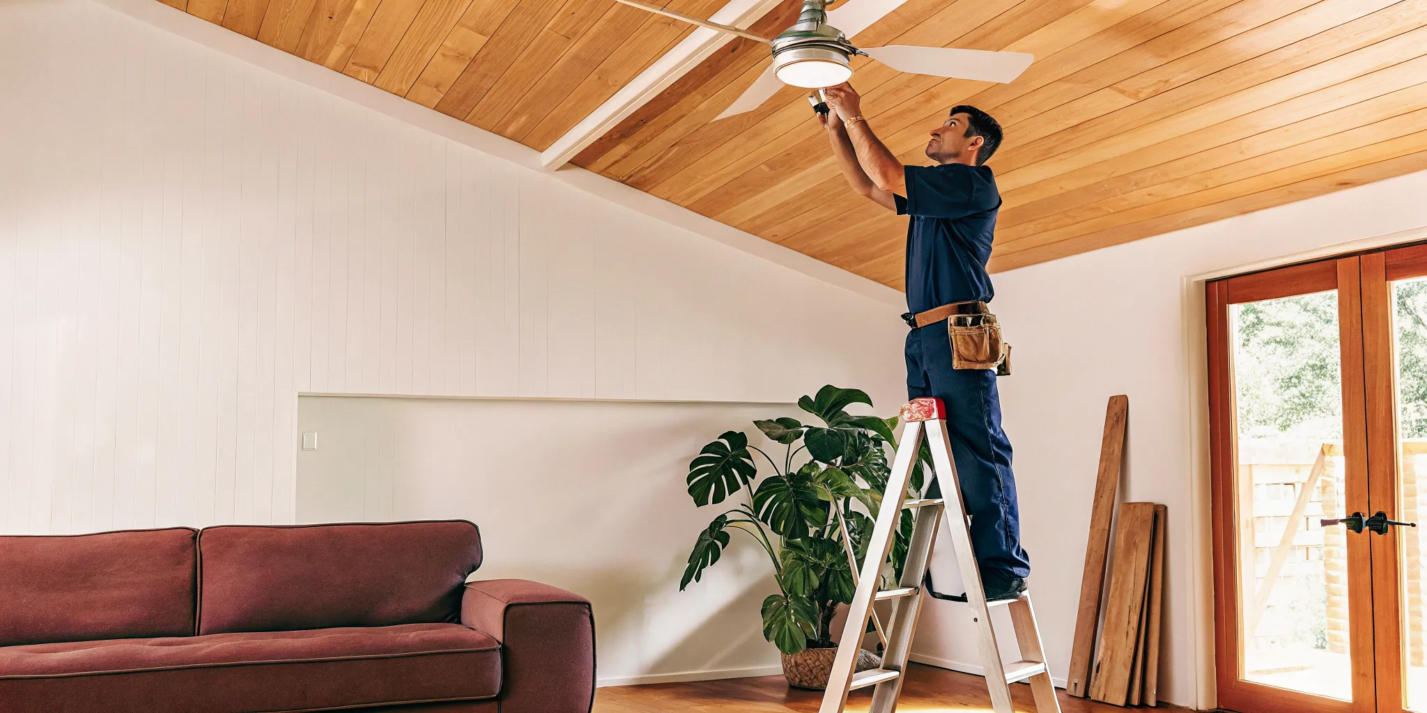 A professional electrician installing a ceiling fan